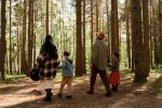 A family enjoys a peaceful walk through a sunlit forest, embracing nature and togetherness.